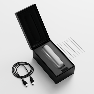 Ploom AURA open box showing the device, its charging cable and cleaning sticks
