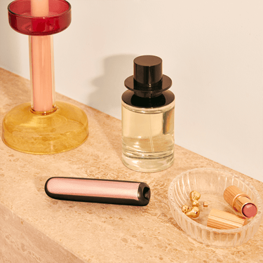 Ploom AURA front panels with Rose Gold Augmented Pattern placed on a dressing table
