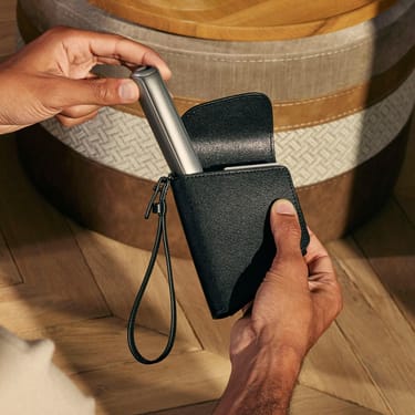 Hand taking a Ploom AURA device out of the Ploom Duo Carry Case Jet Black