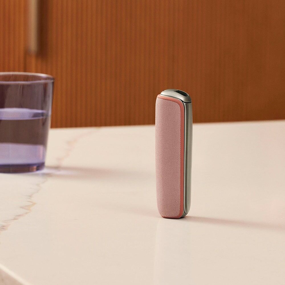 Ploom AURA uređaj sa Rose Gold zadnjom maskom na stolu
